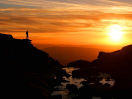 Sunset at Kinder Downfall with walker silhouetted against mountain backdrop