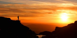 Sunset at Kinder Downfall with walker silhouetted against mountain backdrop