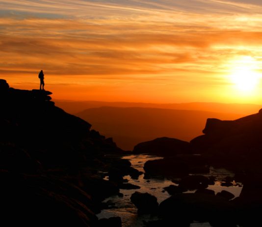 Sunset at Kinder Downfall with walker silhouetted against mountain backdrop