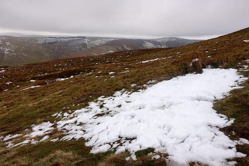 A large patch of snow with distant hills beyond